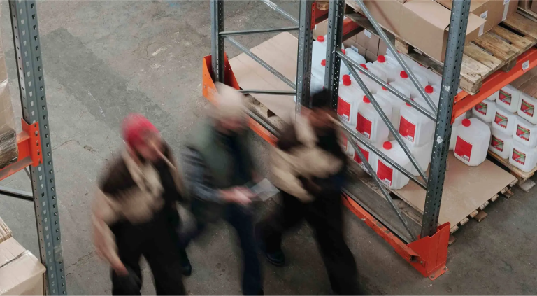 Warehouse workers walking through storage facility aisle with shelves of products